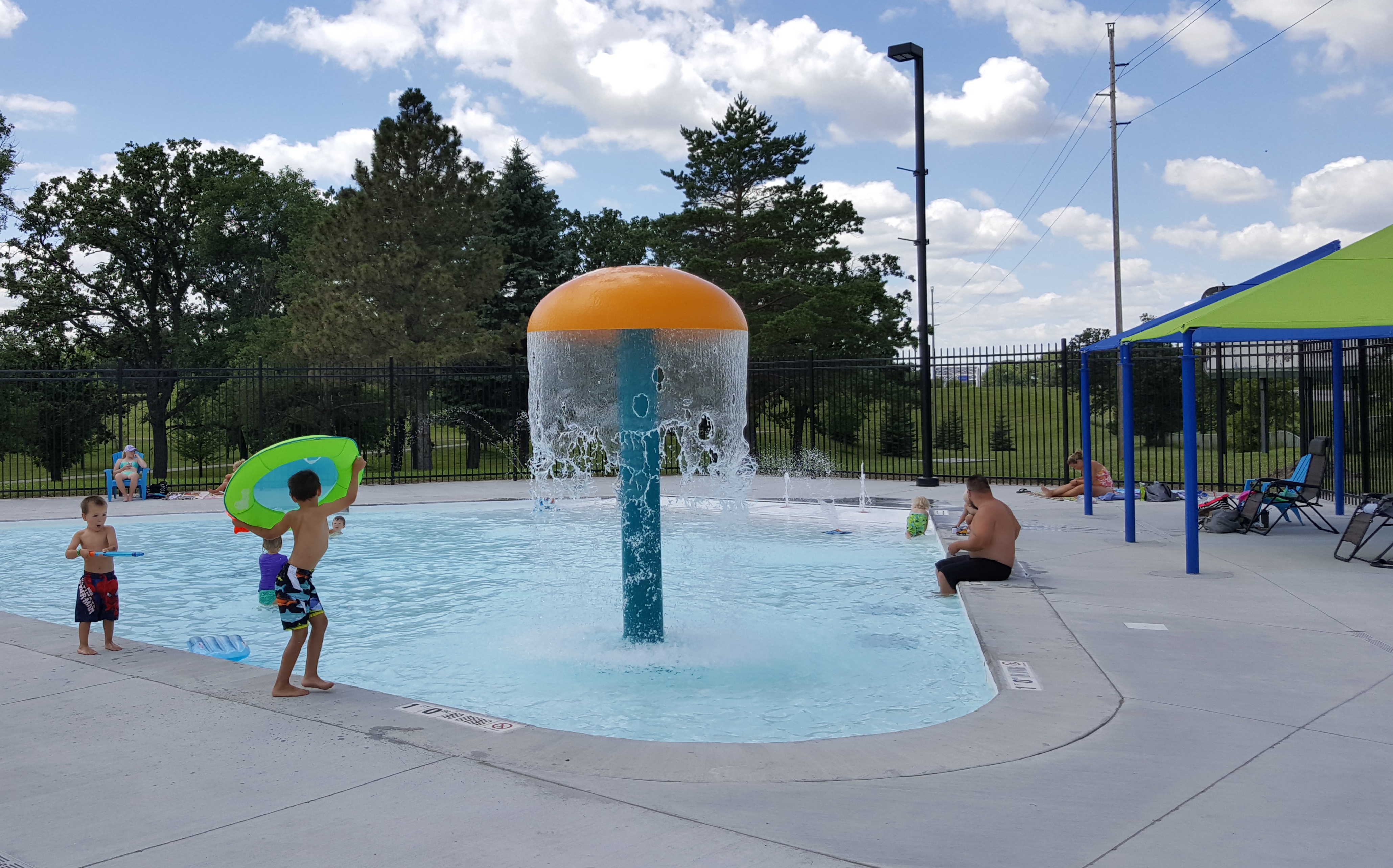 Children playing at a pool with a water feature