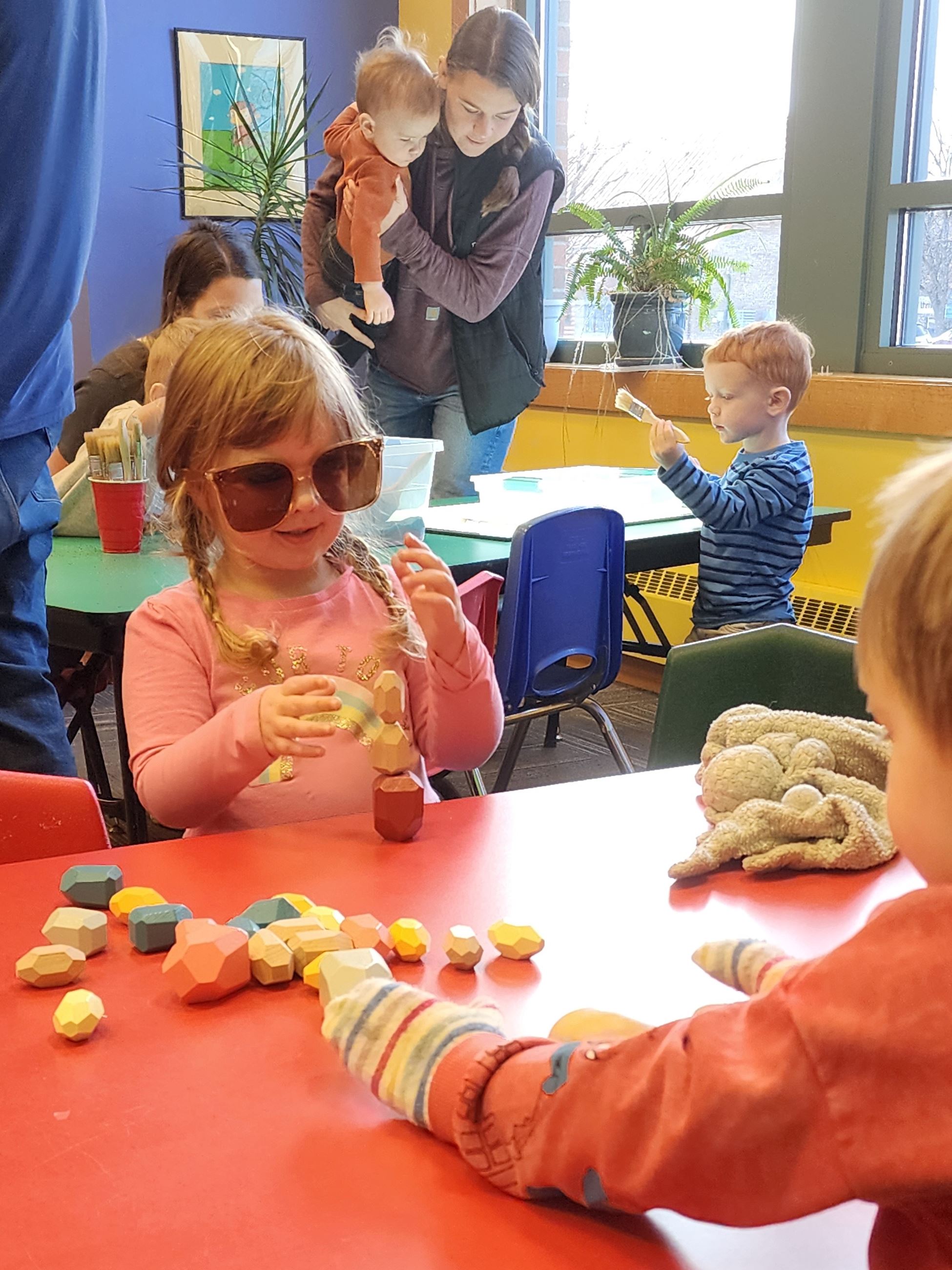 Small children play with geometric shapes at a table